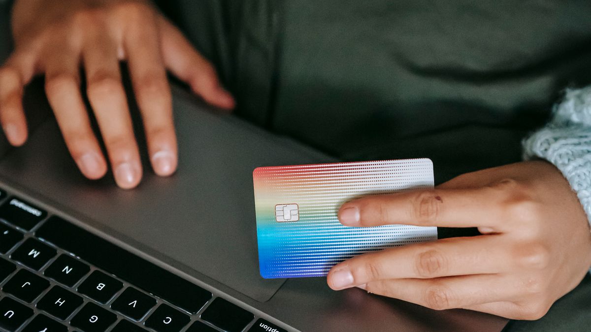 A shopper holding a payment card at a laptop.